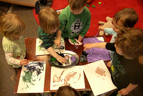 Children painting around a table.