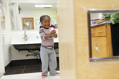 A young girl smiles after washing her hands.