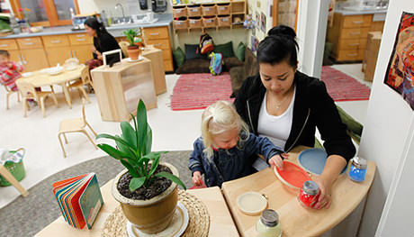 A teacher observes a child arranging plates.