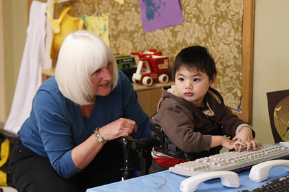 A teacher assisting a young boy with special needs.